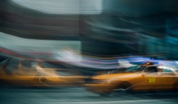 Photo of New York yellow taxis and it's been taken so that the image is blurry, giving a sense of movement.